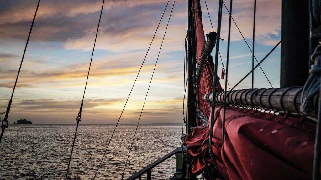 a Pirate Ship floats on the water during sunset.