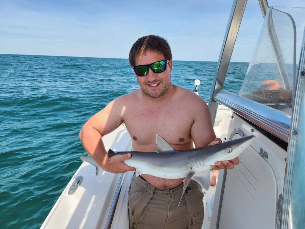 Man holding a shark during a nearshore fishing charter in Myrtle Beach South Carolina