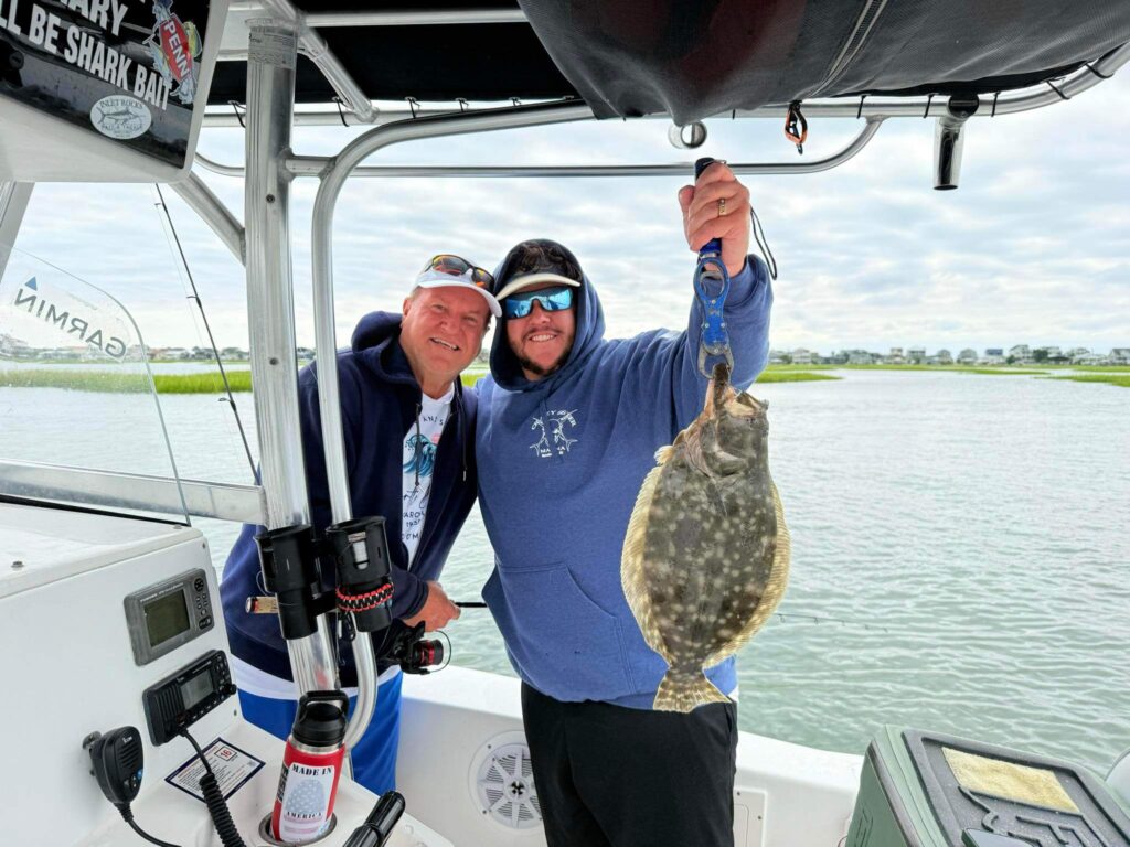 Two anglers holding a flounder catch on a fishing charter boat with Fish Finder Fishing Charters in Florida