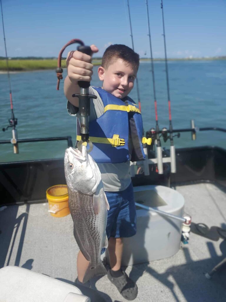 Child holding a redfish on a family fishing charter in Murrells Inlet near Myrtle Beach