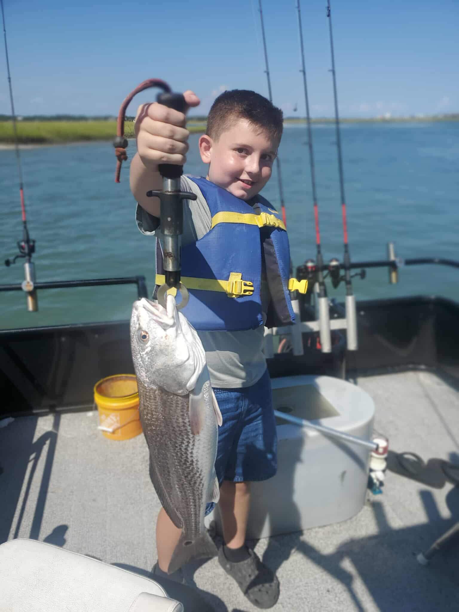 Child holding a redfish on a family fishing charter in Murrells Inlet near Myrtle Beach