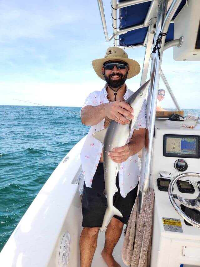 Angler holding a shark on a Murrells Inlet fishing charter in South Carolina ocean waters