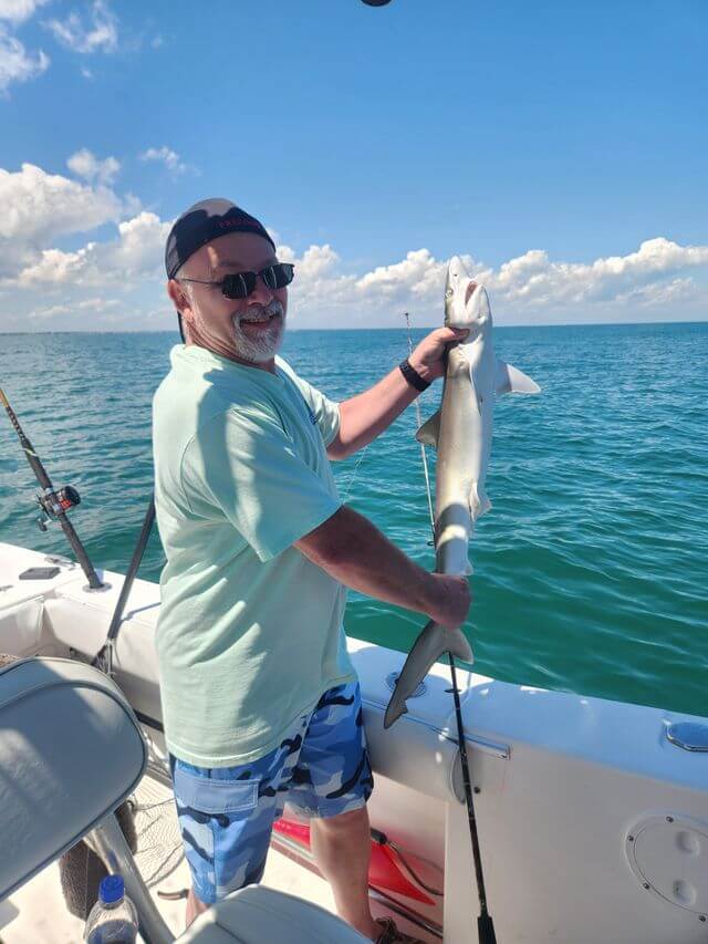 Angler holding a shark on a fishing charter near Myrtle Beach in Murrells Inlet South Carolina