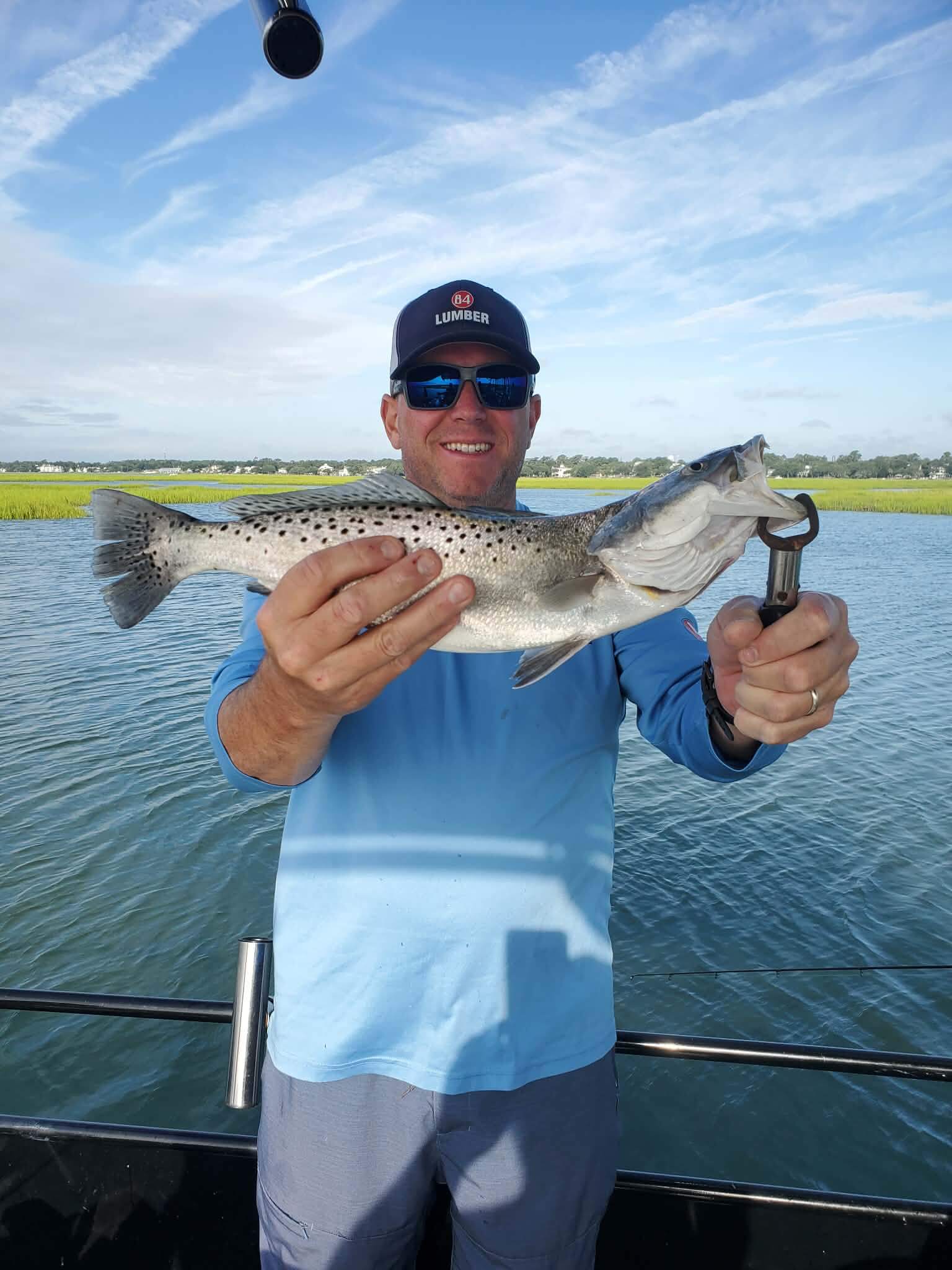Angler holding a speckled trout catch on a fishing charter in Murrells Inlet South Carolina