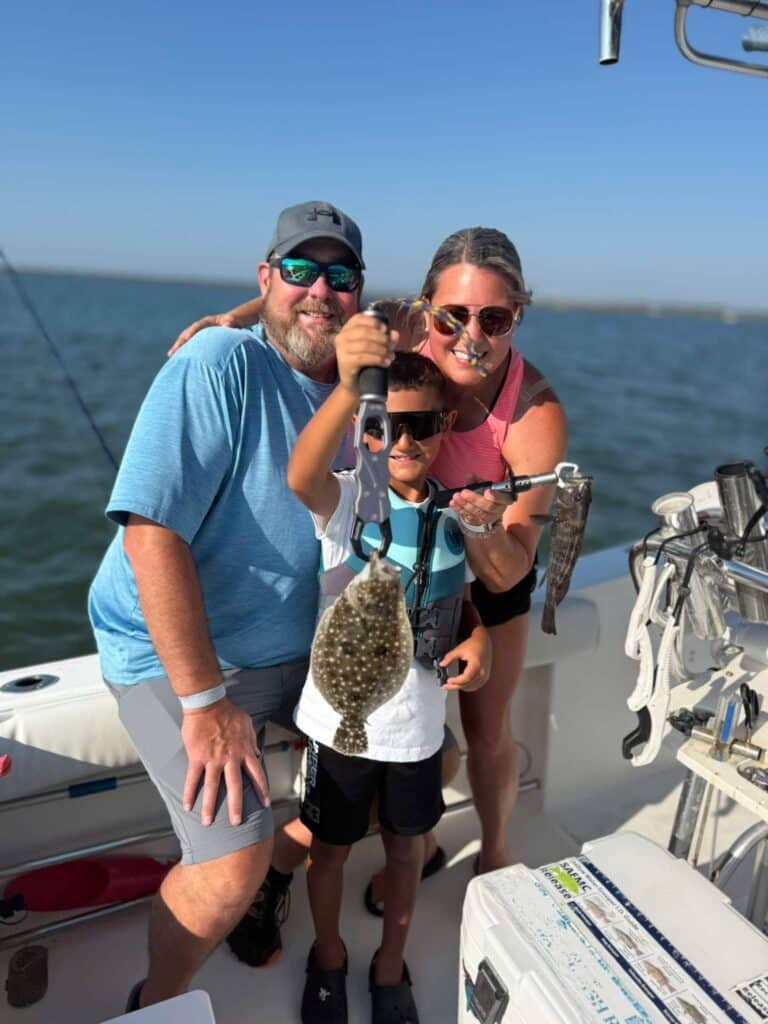 Family smiling as a child holds a flounder during a Murrells Inlet fishing charter