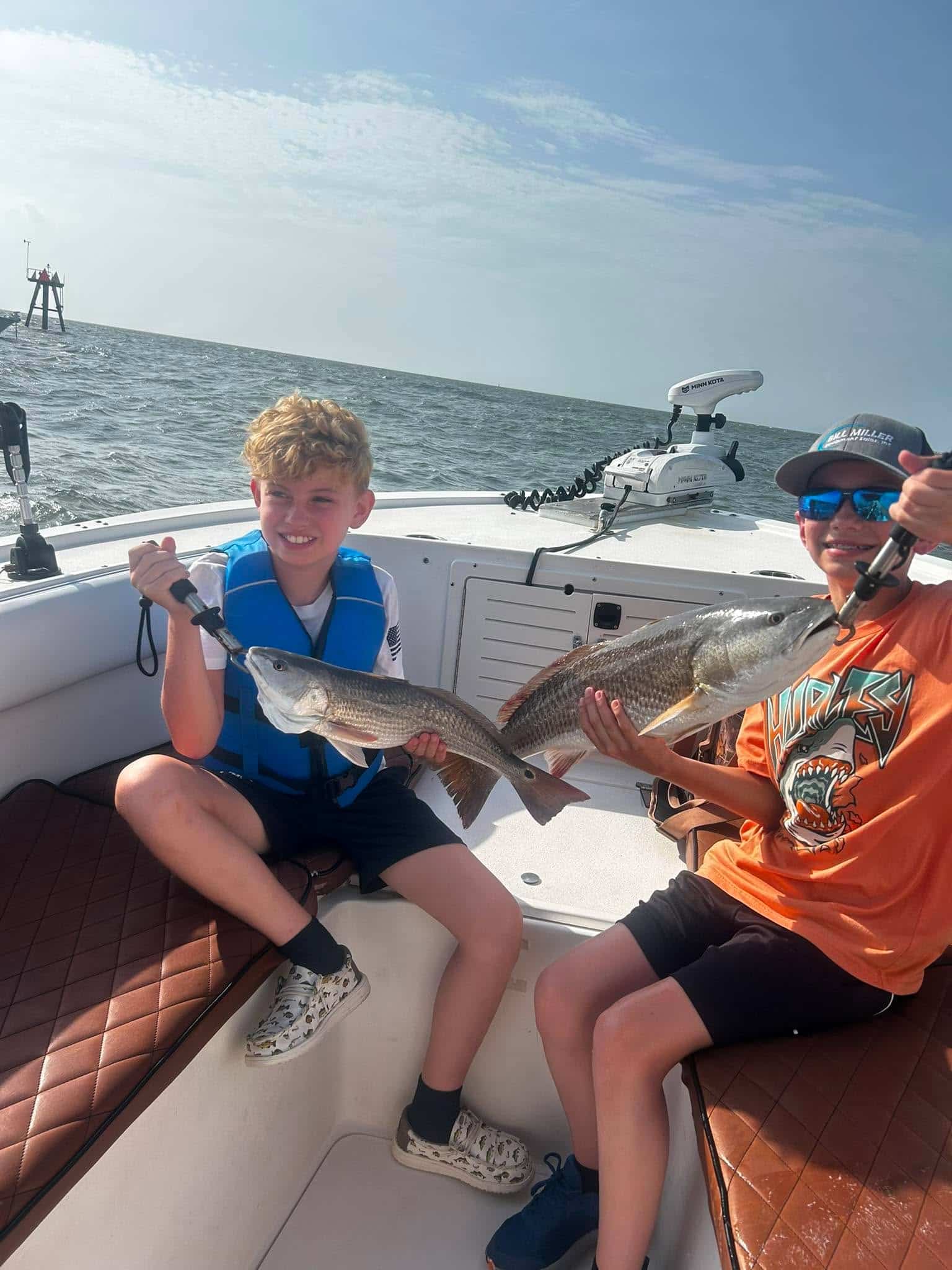 Two children holding redfish during a fishing trip near Murrells Inlet