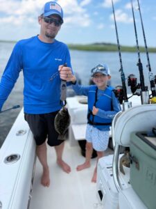 Adult and child holding a flounder on a summer fishing charter in Murrells Inlet