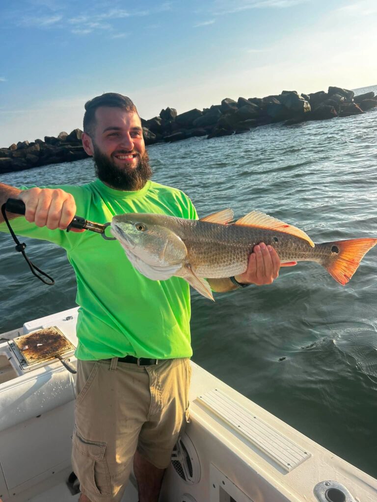 Angler holding a redfish on a boat near the Murrells Inlet jetties