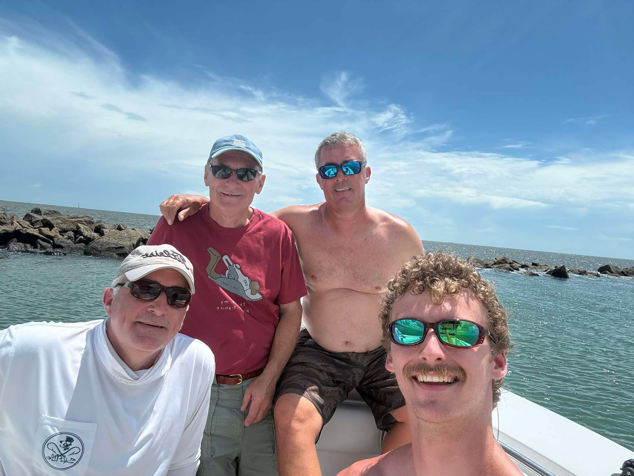 Four anglers smiling together on a fishing boat near the Murrells Inlet jetties