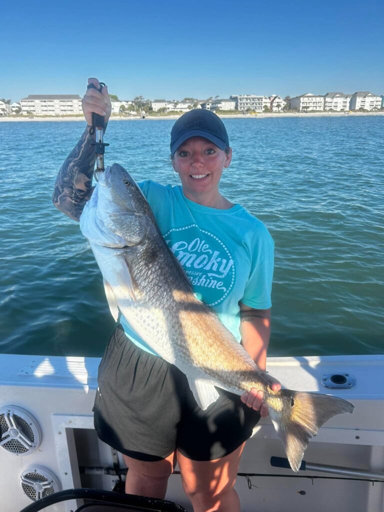 Angler holding a large bull redfish during a fall fishing trip in Murrells Inlet