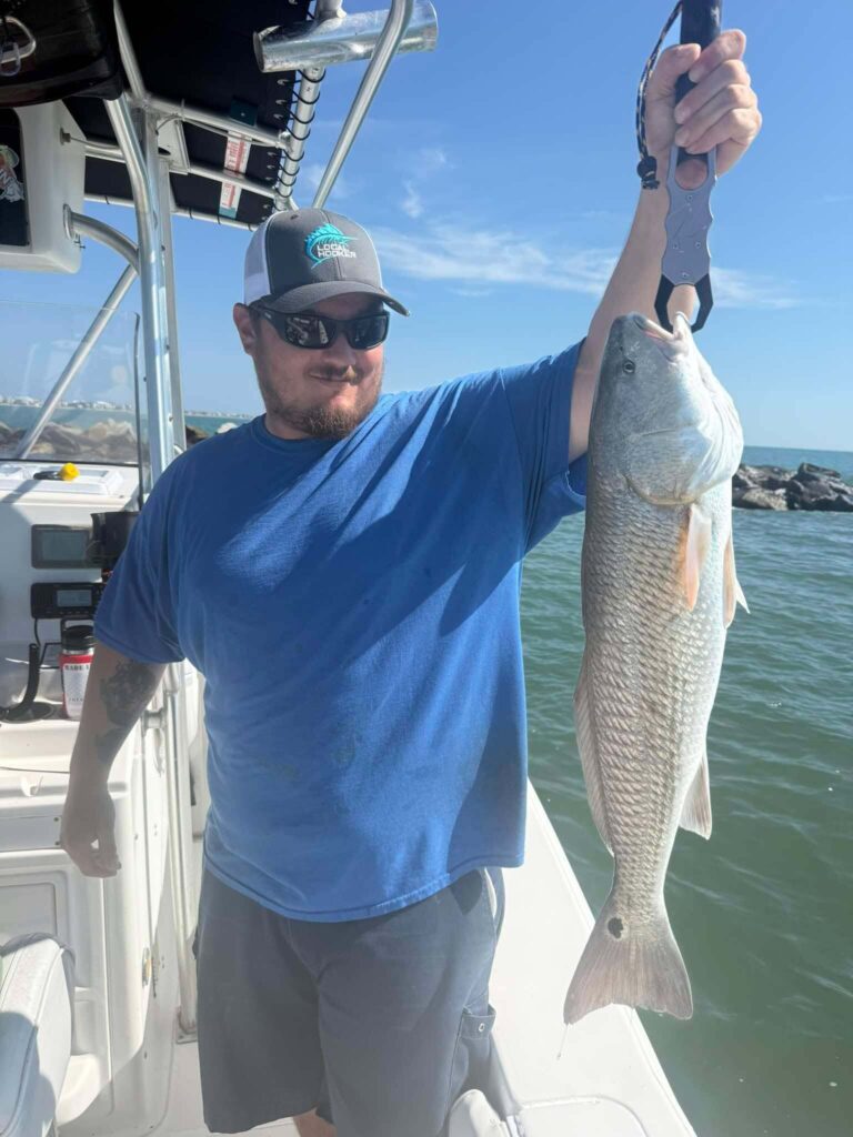 Angler holding a large redfish while fishing near the Murrells Inlet jetties