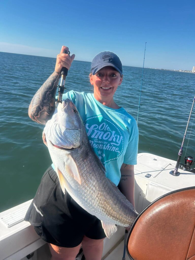Angler holding a large bull redfish on a fishing boat near Murrells Inlet