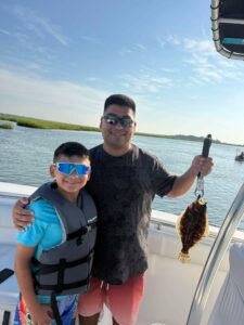 Father and son posing with a flounder during a family fishing trip in Murrells Inlet