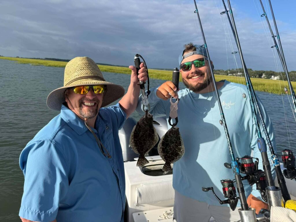 Two anglers holding flounder during a fall inshore fishing trip in Murrells Inlet