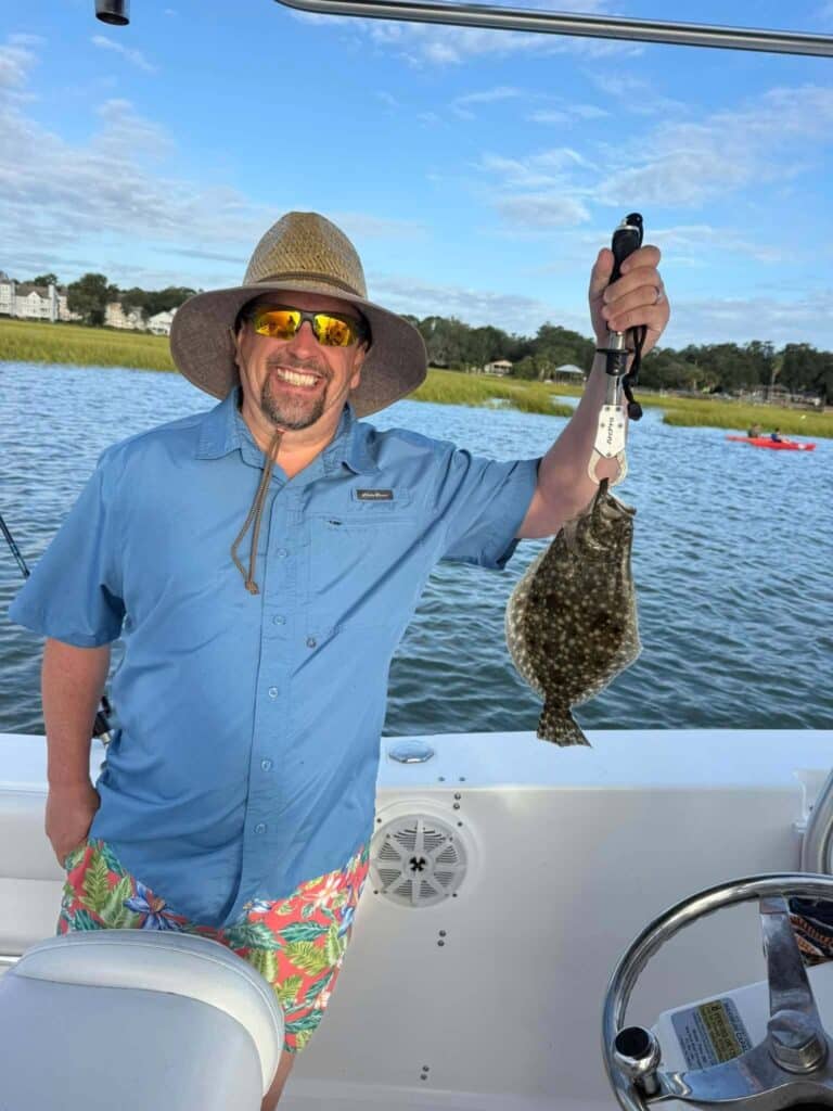 Angler holding a flounder during a fall inshore fishing charter in Murrells Inlet